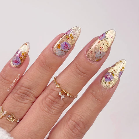 Nails with floral and gold cat eye gel polish designs on a light background